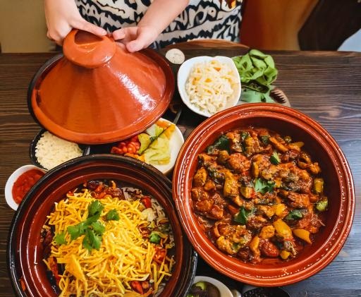 A traditional Moroccan tagine filled with vibrant vegetables and tender meat, surrounded by spices and served on a rustic table.