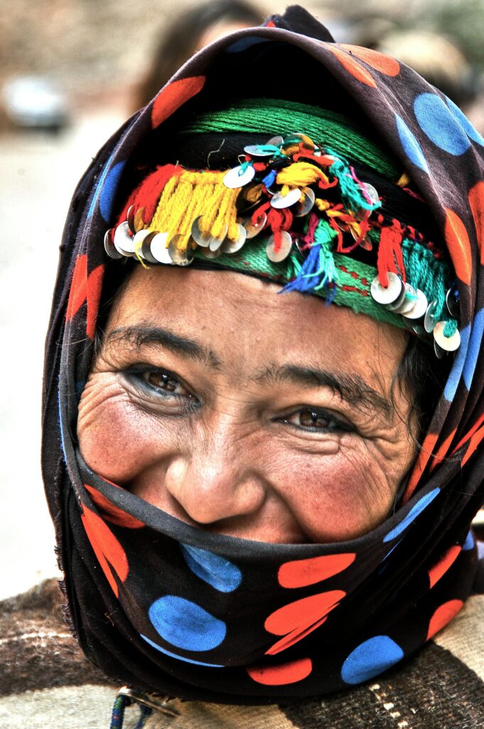 A Berber woman in Morocco wearing traditional Amazigh attire, adorned with silver jewelry and vibrant colors, symbolizing her rich cultural heritage.