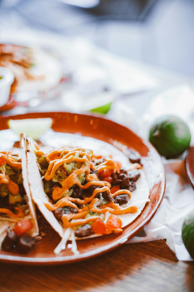 A vibrant plate of traditional Mexican tacos topped with fresh cilantro, onions, and a squeeze of lime, served with a side of salsa and guacamole.