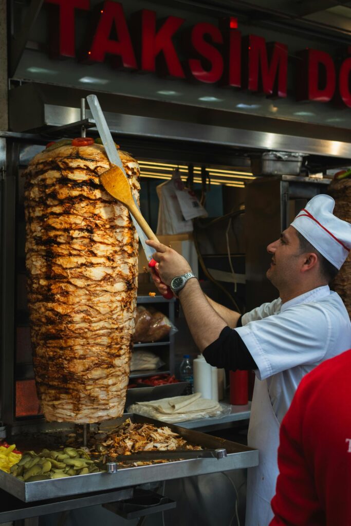 A freshly made Döner wrap stuffed with thinly sliced lamb, fresh lettuce, tomatoes, and a drizzle of yogurt sauce, served on a wooden board.