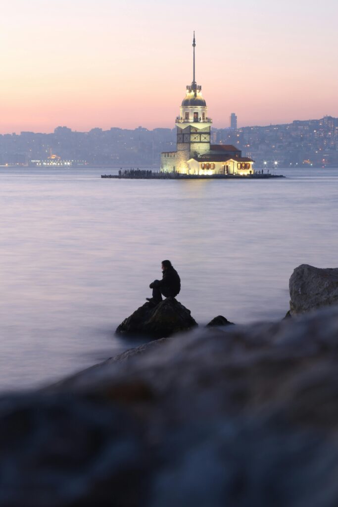 Scenic view of the sea in Istanbul with a towering minaret (menara) silhouetted against a golden sunset, reflecting the city's unique blend of natural beauty and Islamic architecture.